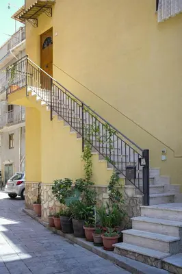 a building with stairs and potted plants on the sidewalk at O Cannulicchiu in Altofonte