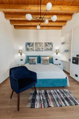 a bedroom with a blue bed and a blue chair at Villa Michela - Dimora di Charme a Cefalù con panorama sul mare by CEFALU BIZ in Cefalù