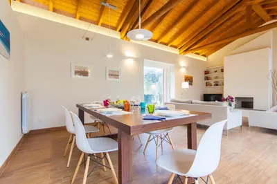 a kitchen and dining room with a wooden table and chairs at Villa dell'Ulivo - by DomuSicily in Terrasini