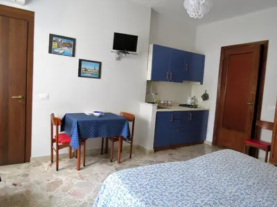 a room with a table and a kitchen with blue cabinets at Appartamento Blu in Palermo