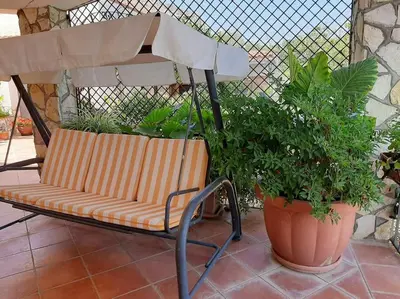 a bench sitting on a patio next to two potted plants at Casa Vacanze Anthea Carini in Carini