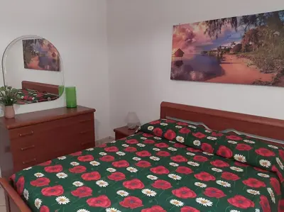 a bedroom with a bed with a green comforter with flowers at Casa Vacanze Anthea Carini in Carini