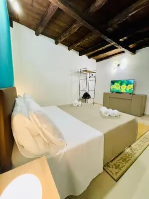 a bedroom with a white bed and a television at Biscottari's home in Palermo