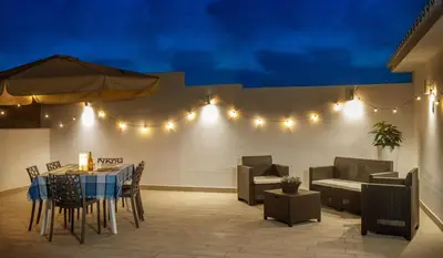 a patio with a table and chairs and lights at Senza Pensieri Holiday Home in Balestrate