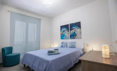 a bedroom with a bed and a blue chair at Senza Pensieri Holiday Home in Balestrate