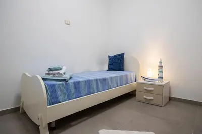 a bedroom with a bed with a blue blanket and a night stand at Senza Pensieri Holiday Home in Balestrate