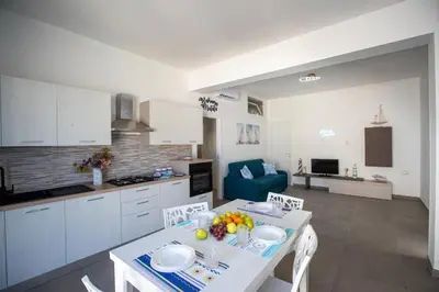 a kitchen and living room with a table and chairs at Senza Pensieri Holiday Home in Balestrate