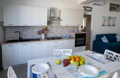 a kitchen with a table with plates and fruit on it at Senza Pensieri Holiday Home in Balestrate