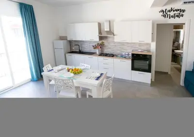 a kitchen with white cabinets and a table and chairs at Senza Pensieri Holiday Home in Balestrate