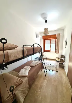 a bedroom with a bed with a floral bedspread and a chair at Rosa's House in Santa Flavia