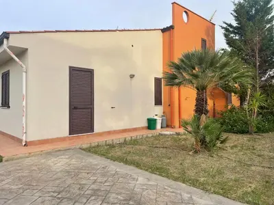 a house with a palm tree in front of it at Villetta 200mt mare e piscina in Campofelice di Roccella