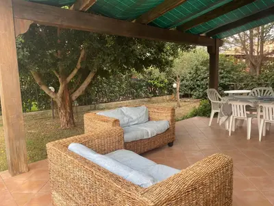 a patio with wicker couches and a table and chairs at Villetta 200mt mare e piscina in Campofelice di Roccella