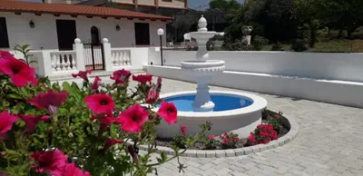 a fountain in the middle of a garden with pink flowers at Villa Nunziatella Badia in Trappeto