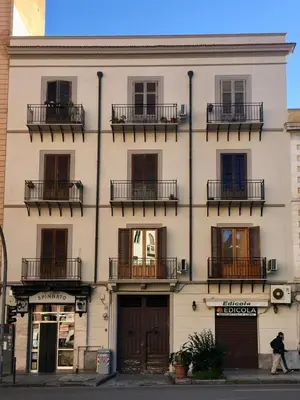a building with balconies and a man walking in front of it at YourLife Suite1 - Deliziosa casa con terrazzino in Palermo