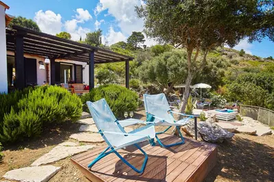 two blue chairs and a table on a wooden deck at Villa Conchiglia - Scopello-Villas in Scopello