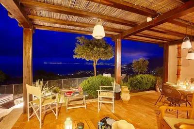 a patio with a view of the ocean at night at Villa Conchiglia - Scopello-Villas in Scopello
