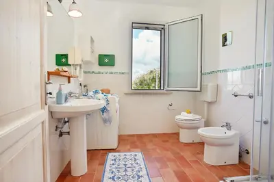 a bathroom with a sink and a toilet and a window at Villa Conchiglia - Scopello-Villas in Scopello
