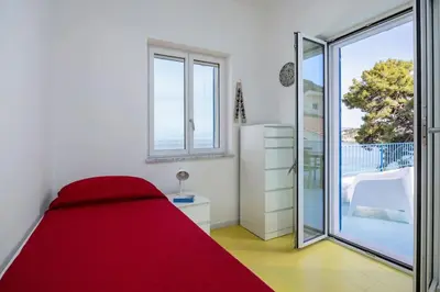 a bedroom with a red bed and a sliding glass door at Terrazza sul mare in Santa Flavia