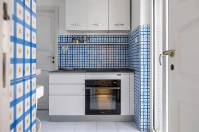 a kitchen with a stove with blue tiles on the wall at Terrazza sul mare in Santa Flavia