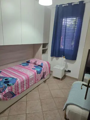 a bedroom with a bed and a blue window at Villetta Viola in San Vito lo Capo