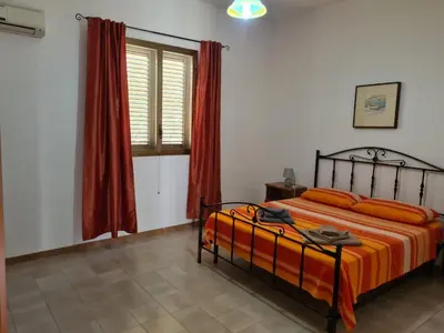 a bedroom with a bed with orange sheets and a window at Casa il Sole Casevacanze Ferienwohnung Daniele Furco in Castellammare del Golfo