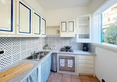 a kitchen with white cabinets and a sink at Solemar Sicilia - Palazzo Eos e Aura in Porticello