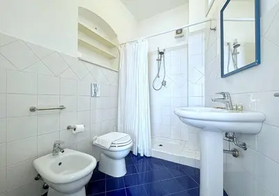 a white bathroom with a toilet and a sink at Solemar Sicilia - Palazzo Eos e Aura in Porticello