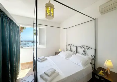 a bedroom with a canopy bed with a view of the ocean at Solemar Sicilia - Palazzo Eos e Aura in Porticello