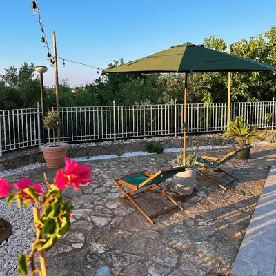 two chairs and an umbrella on a patio at Cocciu D'amuri Home - Scopello in Scopello