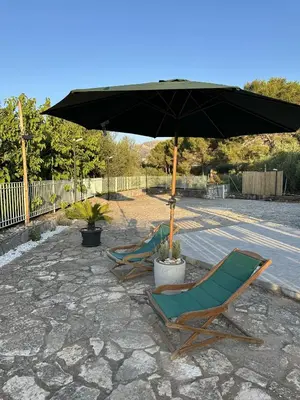 two lawn chairs and an umbrella on a patio at Cocciu D'amuri Home - Scopello in Scopello