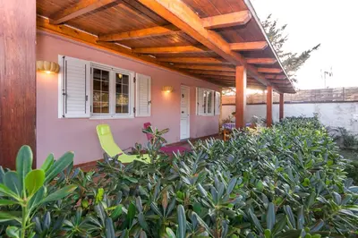 a patio with a wooden pergola and some bushes at Villa Cicas sul mare in Campofelice di Roccella