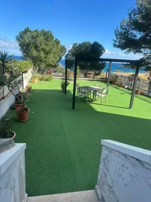 a patio with a table and chairs on the grass at La Terrazza del Sole in Lido di Mondello