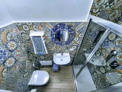 a bathroom with a toilet and a mosaic wall at Seafront House Gabbiano Blu in Santa Flavia