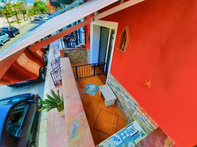 a red building with a bench next to a street at Seafront House Gabbiano Blu in Santa Flavia