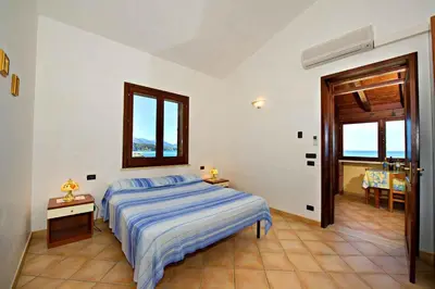 a bedroom with a bed and a window and a table at Blunda Holiday Home in Castellammare del Golfo