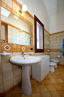 a bathroom with a sink and a mirror and two toilets at Blunda Holiday Home in Castellammare del Golfo