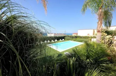 a swimming pool with chairs and a palm tree at Villa Dwellings With Pool For Exclusive Use in Alcamo
