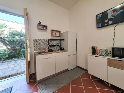 a kitchen with white cabinets and a tv on the wall at Holiday Home Maya's Home Palermo by Interhome in Palermo