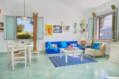 a living room with a blue couch and a table at Villa Sirena - Scopello-Villas in Scopello