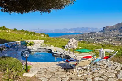 a swimming pool with two chairs and a table at Villa Sirena - Scopello-Villas in Scopello