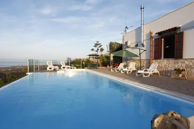 a swimming pool with chairs and a house at Villa del Poggio in Scopello