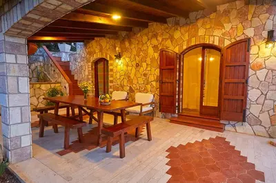 a patio with a wooden table and a stone wall at Villa del Poggio in Scopello