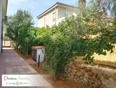 a fence with a bush next to a house at Domus Amelio - Country Rooms in Cinisi