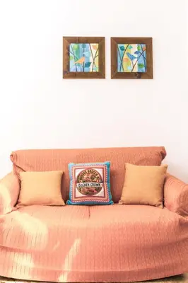an orange couch with two pictures on the wall at Casa Dorotea in Balestrate