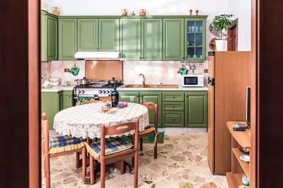 a kitchen with green cabinets and a table with chairs at Casa Dorotea in Balestrate