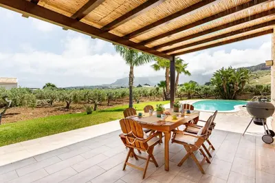 a patio with a table and chairs and a pool at Villa delle Stelle in Scopello
