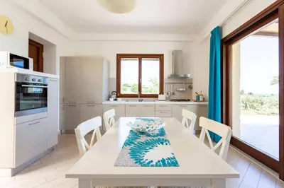 a kitchen with a white table and chairs and a kitchen with a window at Villa delle Stelle in Scopello
