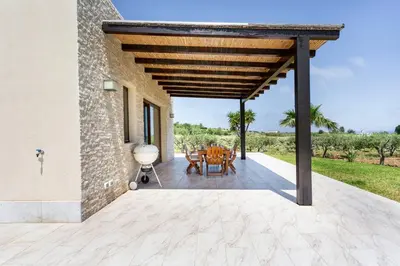 an outdoor patio with a wooden pergola at Villa delle Stelle in Scopello