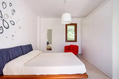 a bedroom with a bed and a red chair at Villa delle Stelle in Scopello