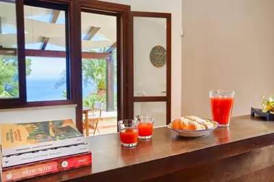a table with a bowl of bread and two glasses of orange juice at Villa del Drago in Scopello